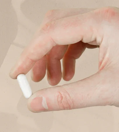 Hand hält eine weiße Kapsel